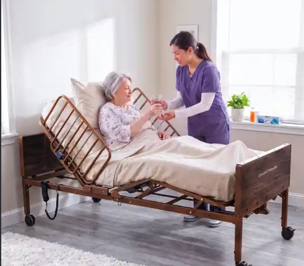 Caregiver helping a patient in an adjustable electronic medical bed at home
